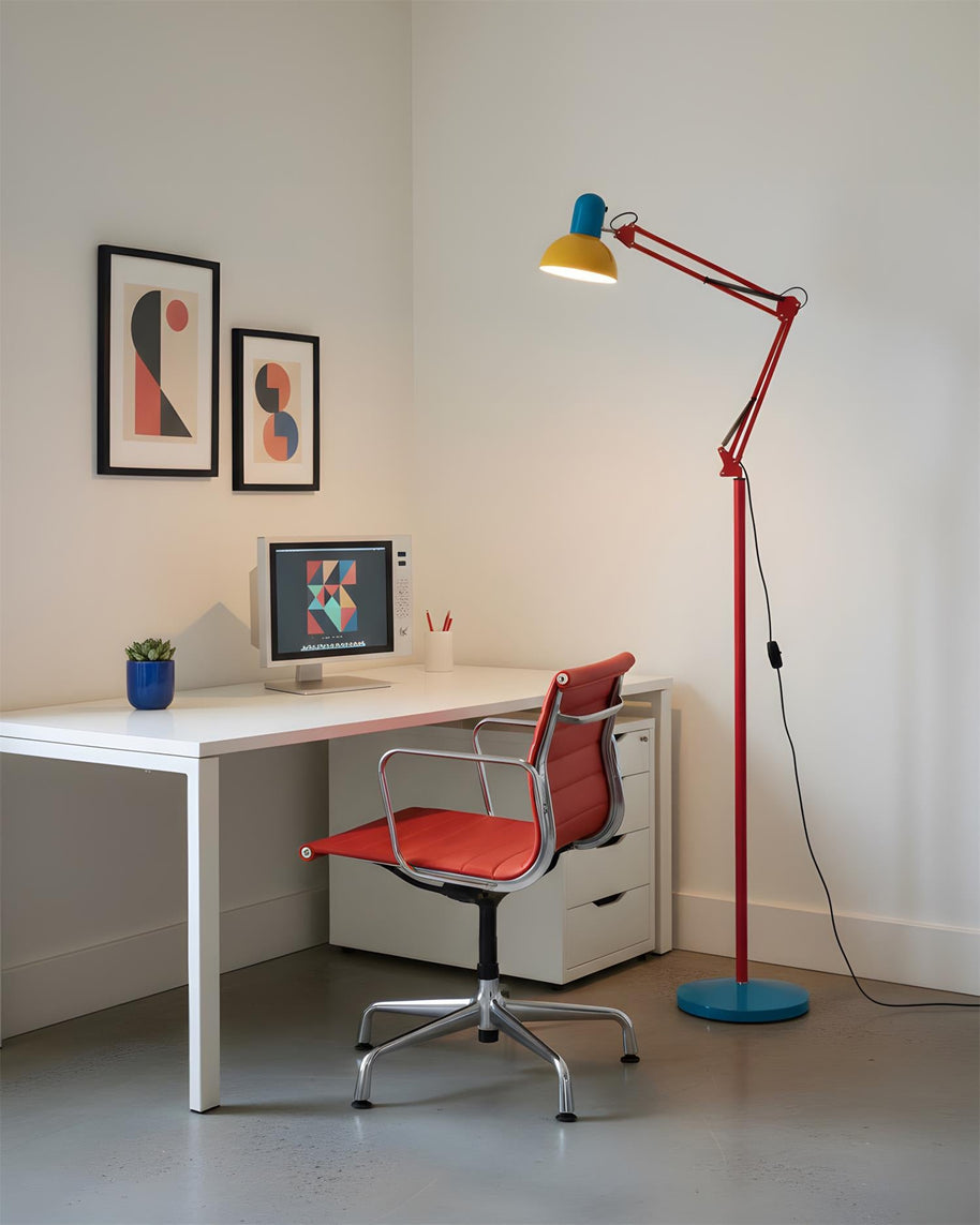 Adjustable floor lamp with a red arm, yellow shade and round blue base beside a white desk and a red office chair.