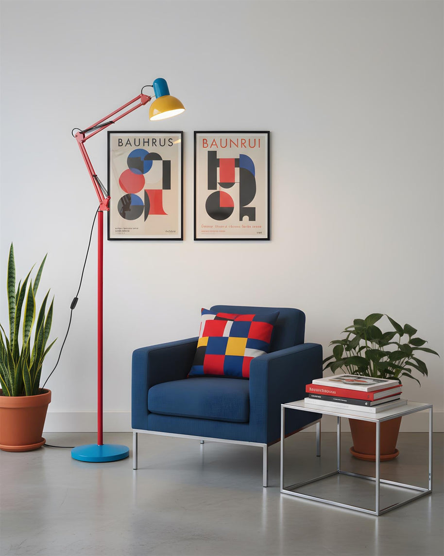 Adjustable floor lamp with a red arm, yellow shade and round blue base beside a blue armchair below two framed prints.