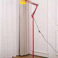 Adjustable floor lamp with a red arm, yellow shade and round blue base beside a white curtain and door.