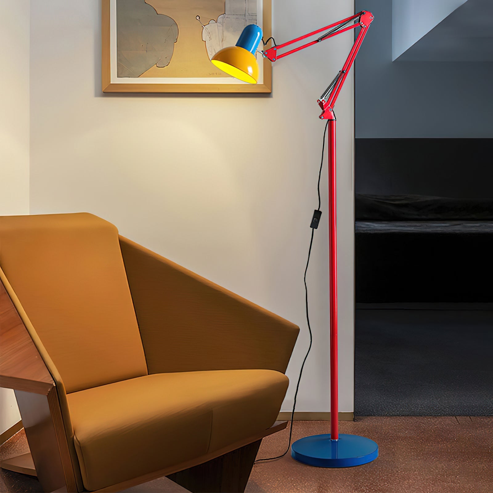 Adjustable floor lamp with a red arm, yellow shade and round blue base lit beside a mustard sofa under a framed picture.