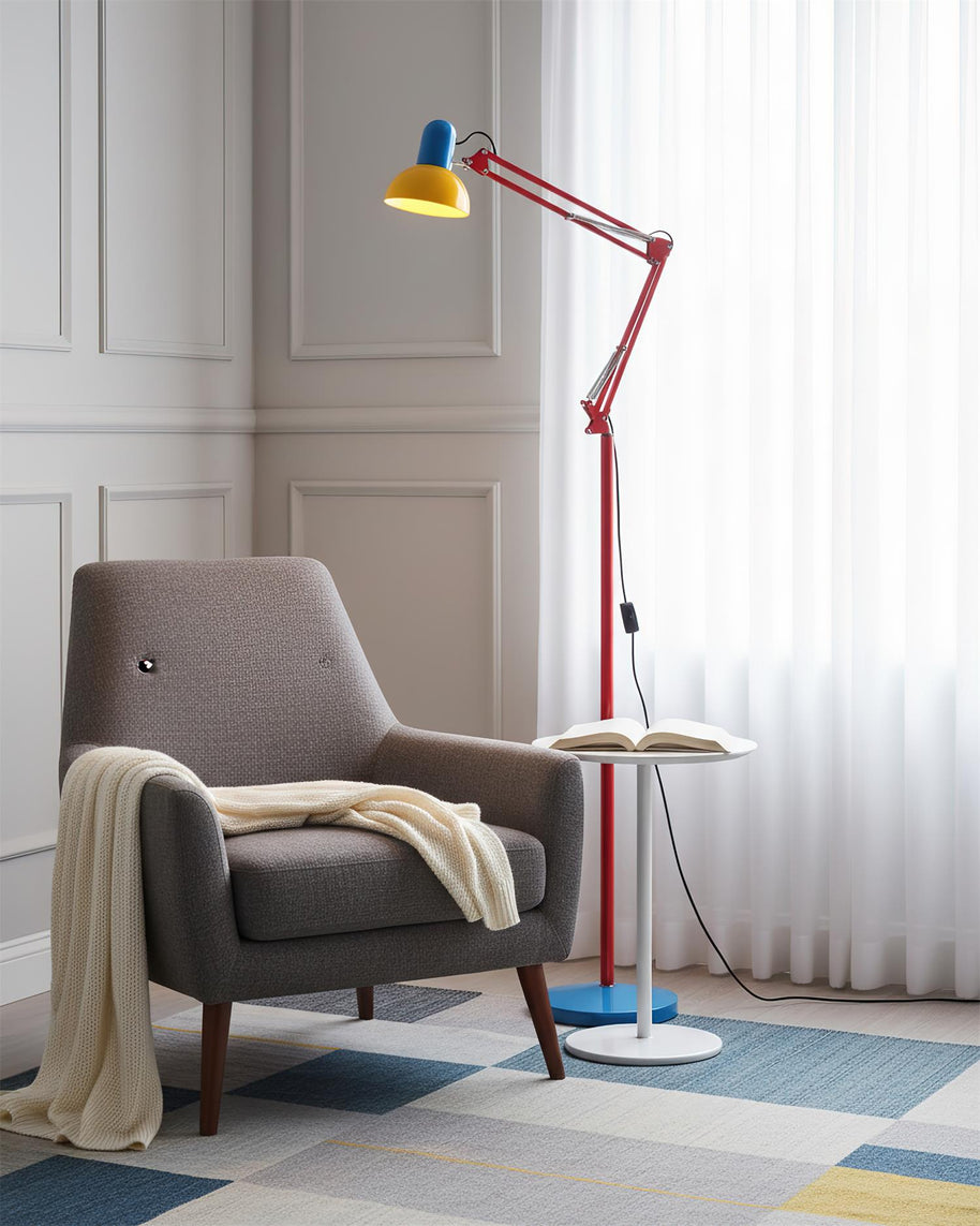 Adjustable floor lamp with a red arm, yellow shade and round blue base beside a grey armchair with a throw.
