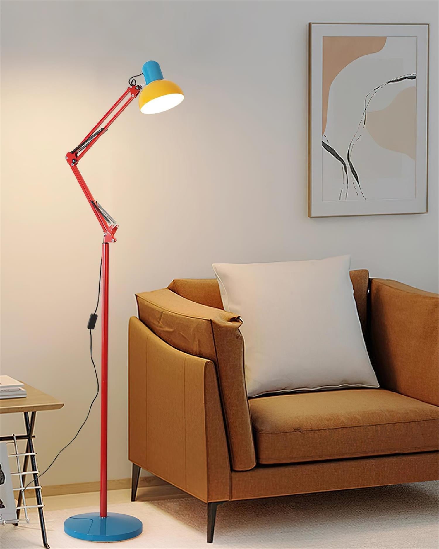 Adjustable floor lamp with a red arm, yellow shade and round blue base beside a tan armchair in a living room.