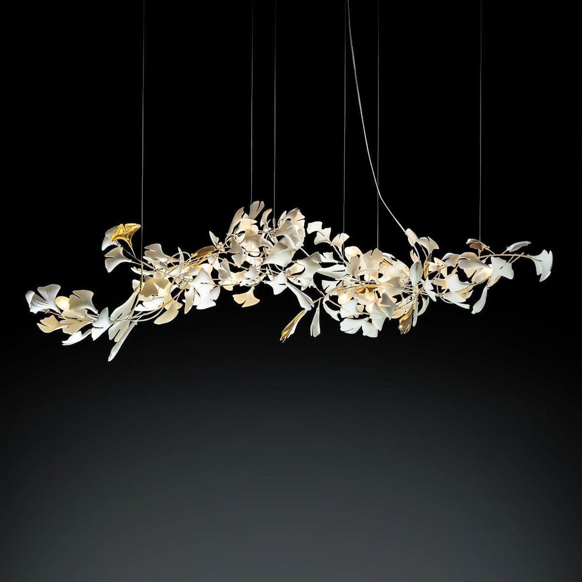 Gold-branch porcelain ginkgo chandelier lit against a dark studio background.