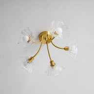 Flush-mount ceiling lamp with curved brass arms holding clear ribbed flower-shaped glass shades, unlit, seen from below.