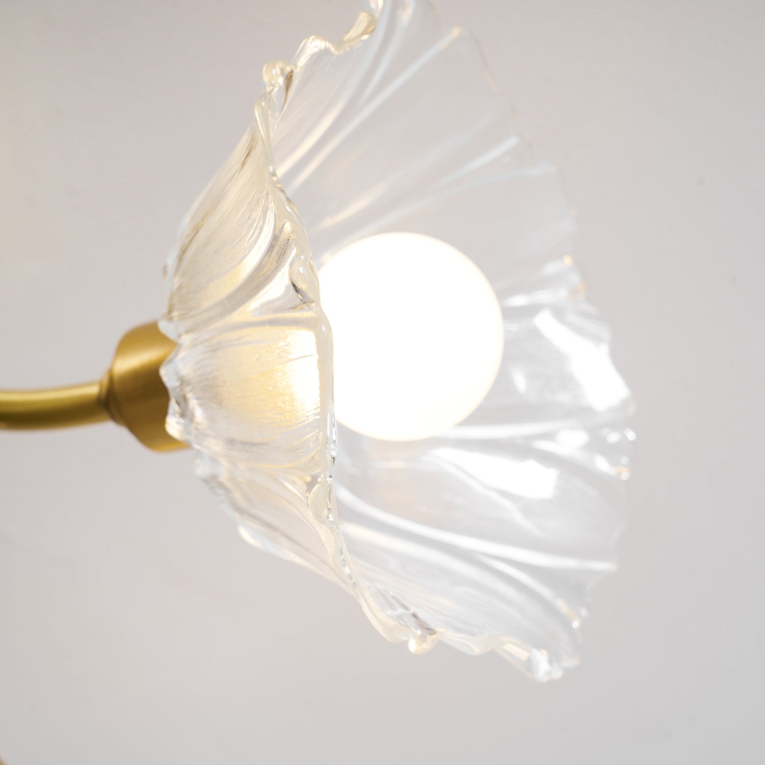 Close view of one flower-shaped glass shade with the bulb lit inside.