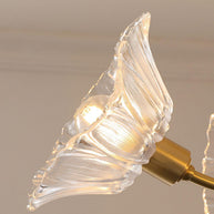 Close view of one clear flower-shaped glass shade on its brass arm.