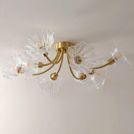 Flush-mount ceiling lamp with curved brass arms holding clear ribbed flower-shaped glass shades, lit, seen close from below.