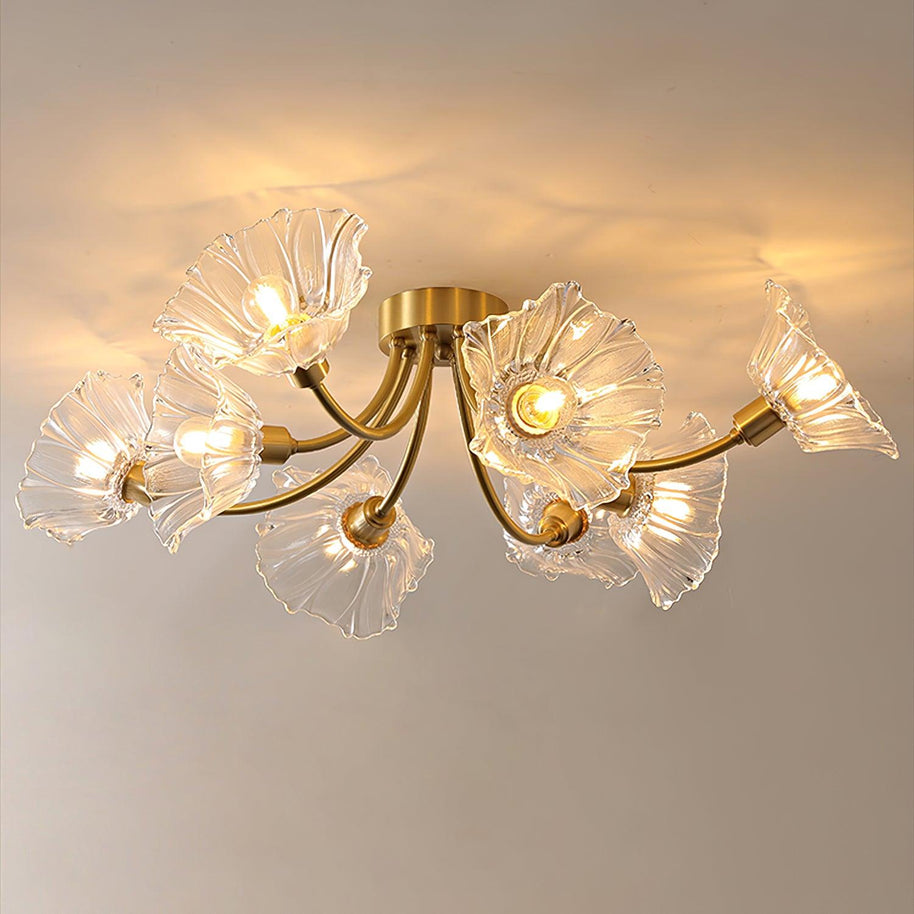 Flush-mount ceiling lamp with curved brass arms holding clear ribbed flower-shaped glass shades, lit, with the arms spread wide across the ceiling.