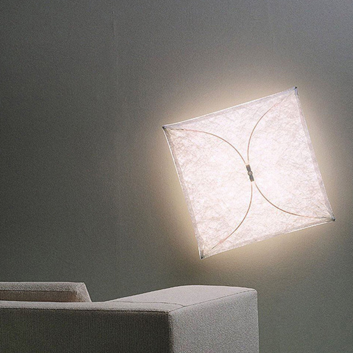 Kivora Wall Light, tilted square paper panel glowing on a grey wall above a boucle sofa