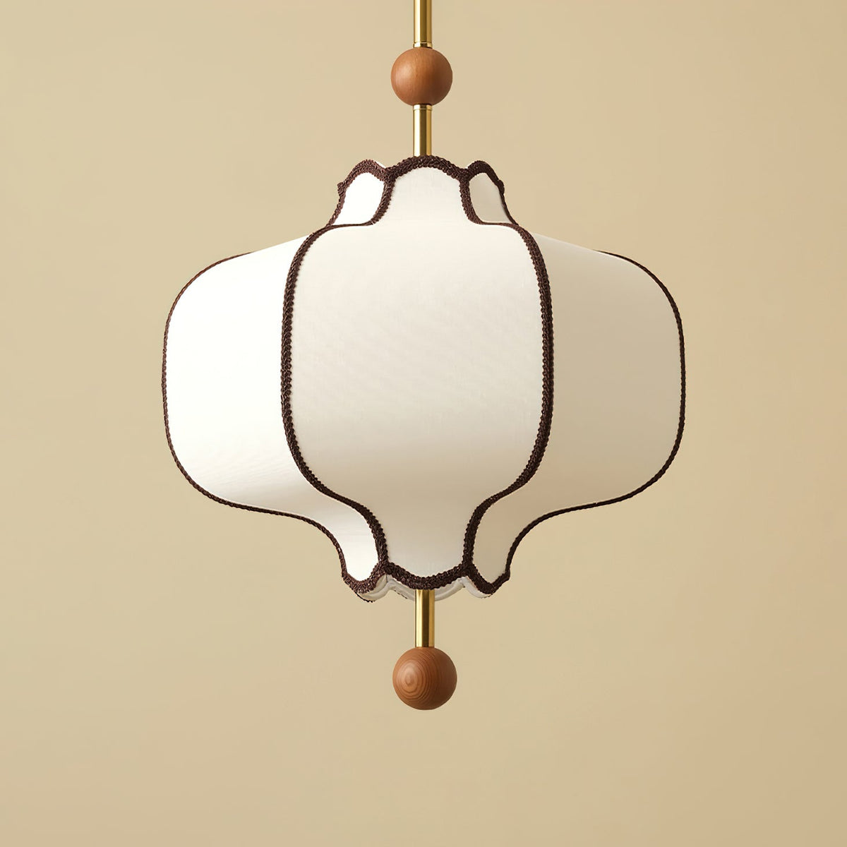 Close view of a lit white fabric lantern shade edged in brown braid on a brass rod.