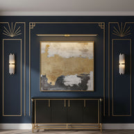Gold slim linear LED wall light mounted above a framed artwork on a deep navy panelled wall