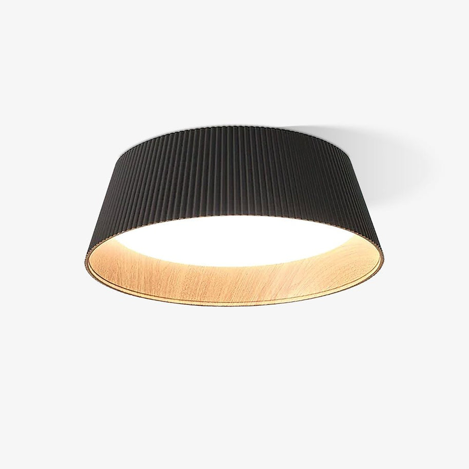 Drum-shaped flush ceiling light with a ribbed black outer, a wood-look inner rim and a white diffuser, lit, on a white background.