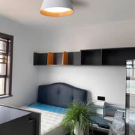 Drum-shaped flush ceiling light with a ribbed white outer, a wood-look inner rim and a white diffuser fitted to a ceiling above a desk and shelves.