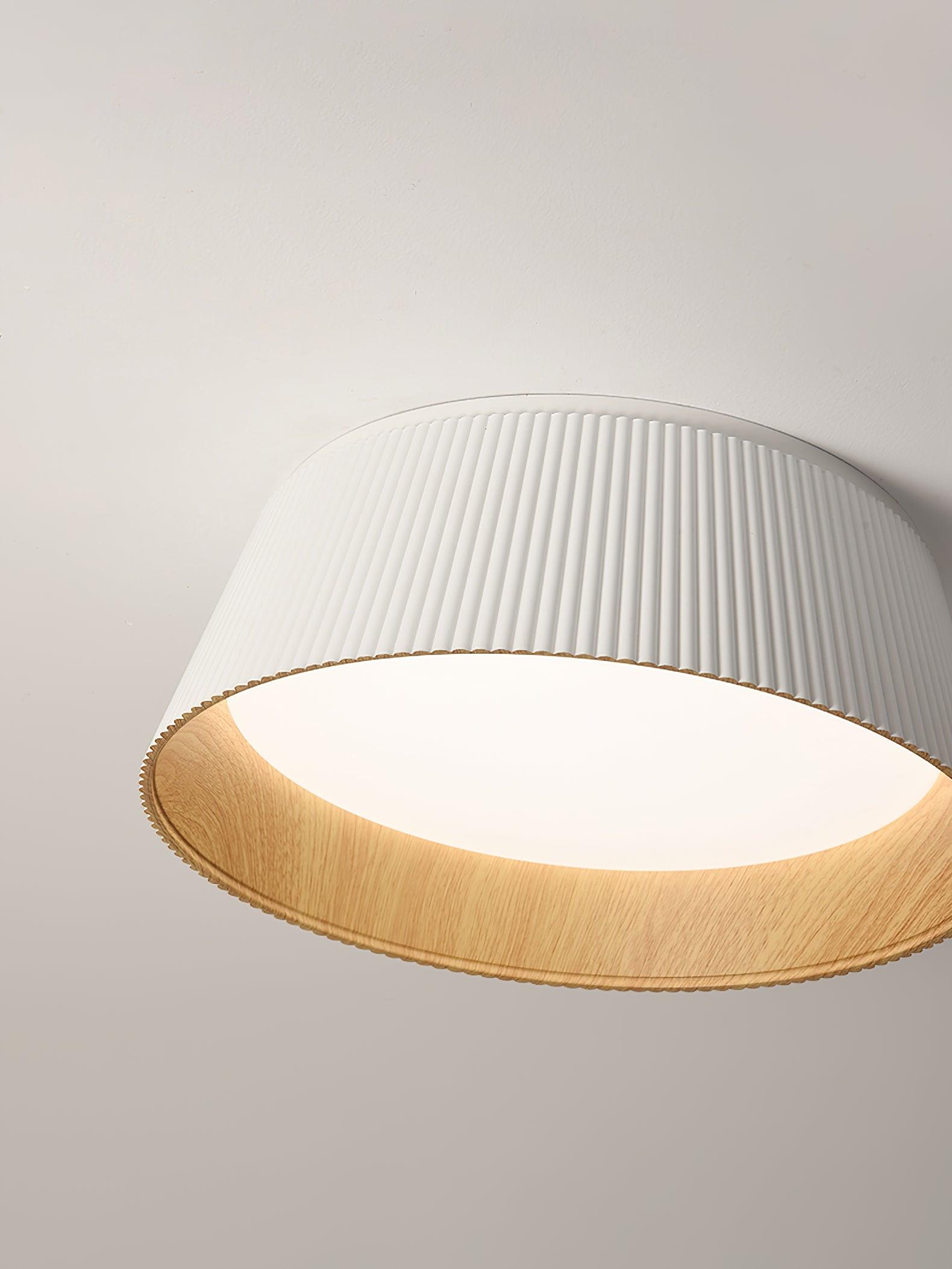 Drum-shaped flush ceiling light with a ribbed white outer, a wood-look inner rim and a white diffuser, seen from below at an angle.