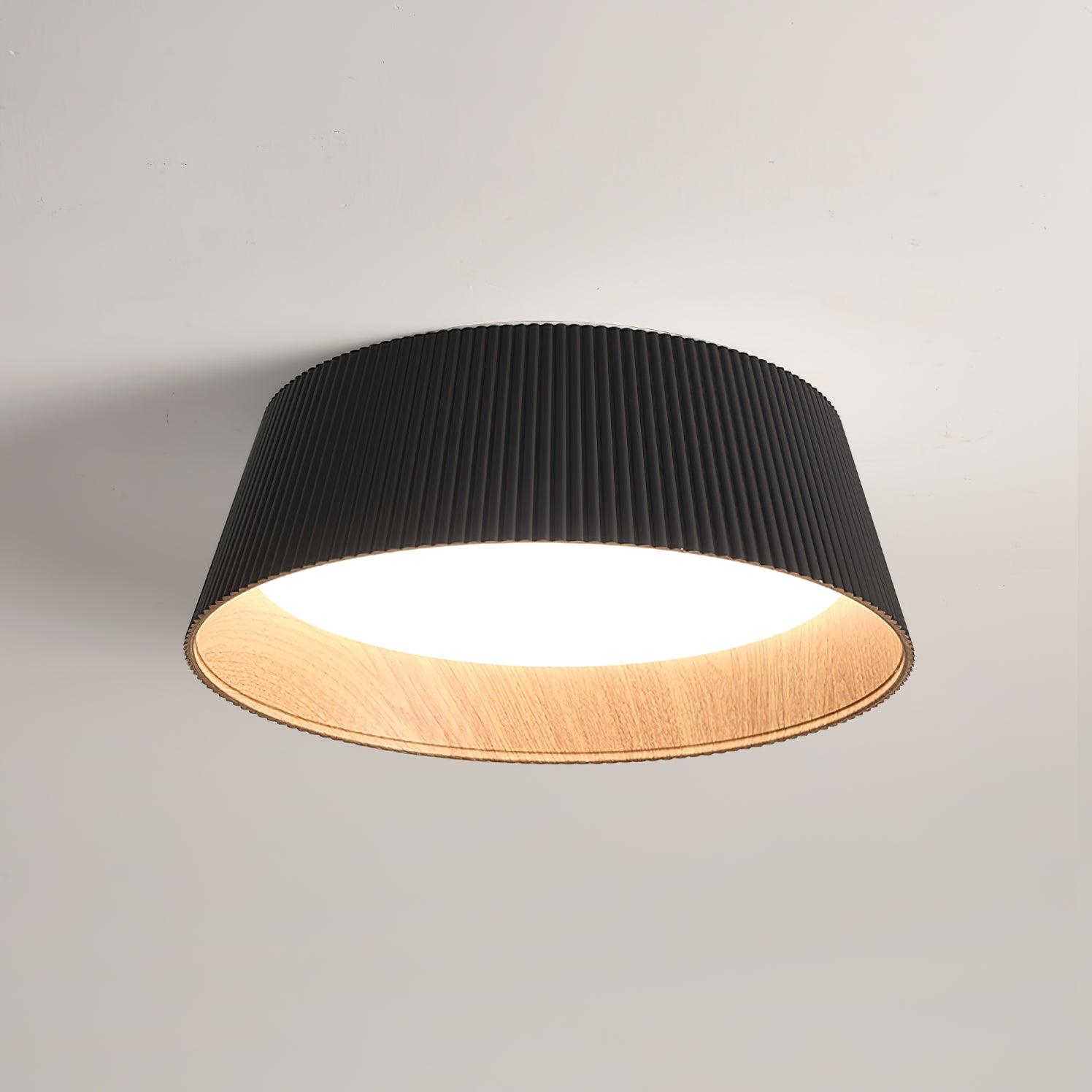Drum-shaped flush ceiling light with a ribbed shade, a wood-look inner rim and a white diffuser, dark ribbed shade, lit, seen from below on a plain background.