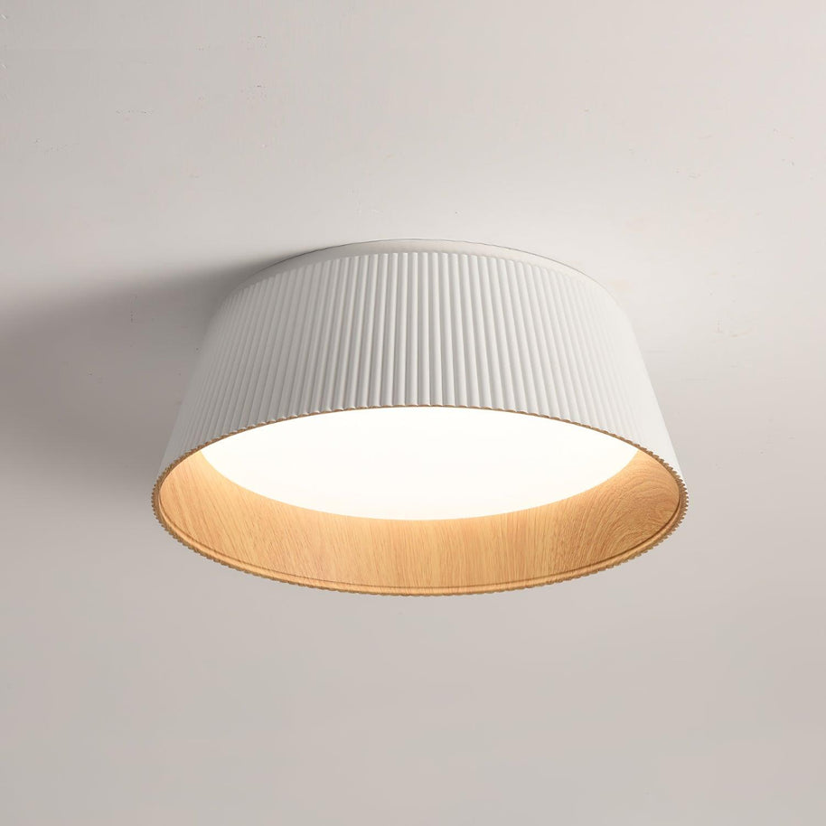 Drum-shaped flush ceiling light with a ribbed white outer, a wood-look inner rim and a white diffuser, lit, seen at an angle on a plain background.