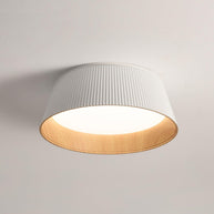 Drum-shaped flush ceiling light with a ribbed white outer, a wood-look inner rim and a white diffuser, lit, seen at an angle on a plain background.