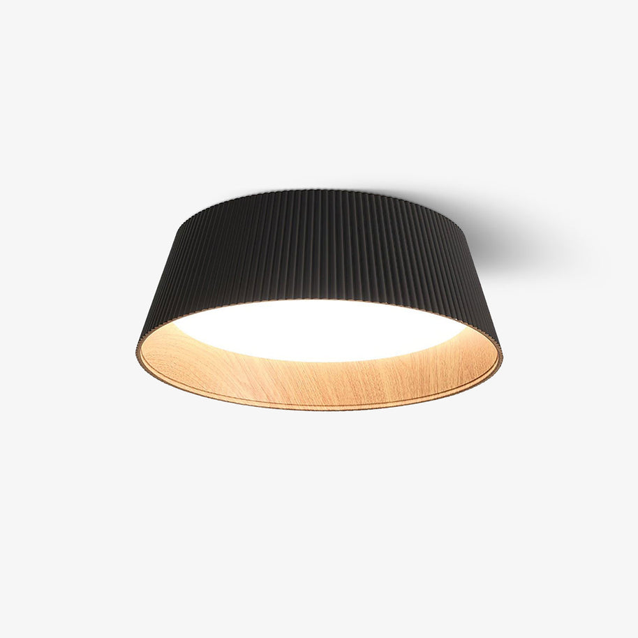 Drum-shaped flush ceiling light with a ribbed black outer, a wood-look inner rim and a white diffuser, lit, on a plain background.