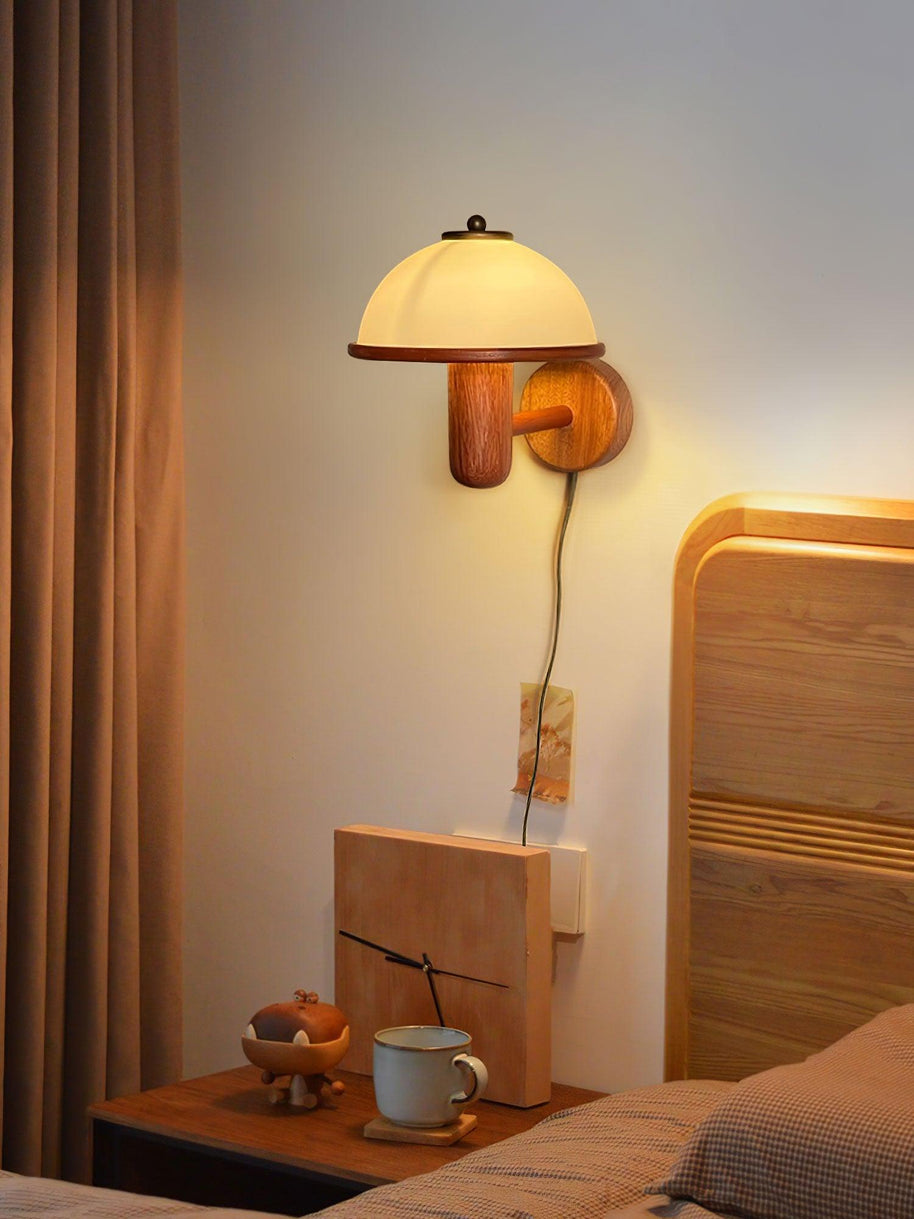 Mushroom Wood Wall Lamp lit above a bedside table with flowers