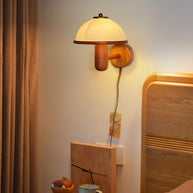 Mushroom Wood Wall Lamp lit above a bedside table with flowers