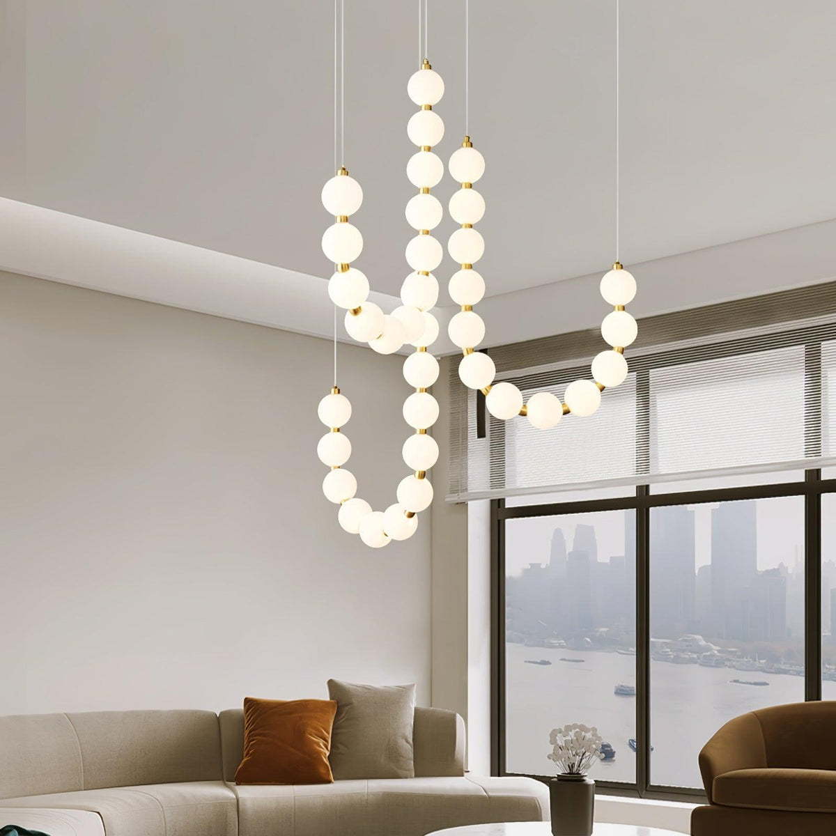 Perloria Chandelier, lit opal globe strands above a living room sofa