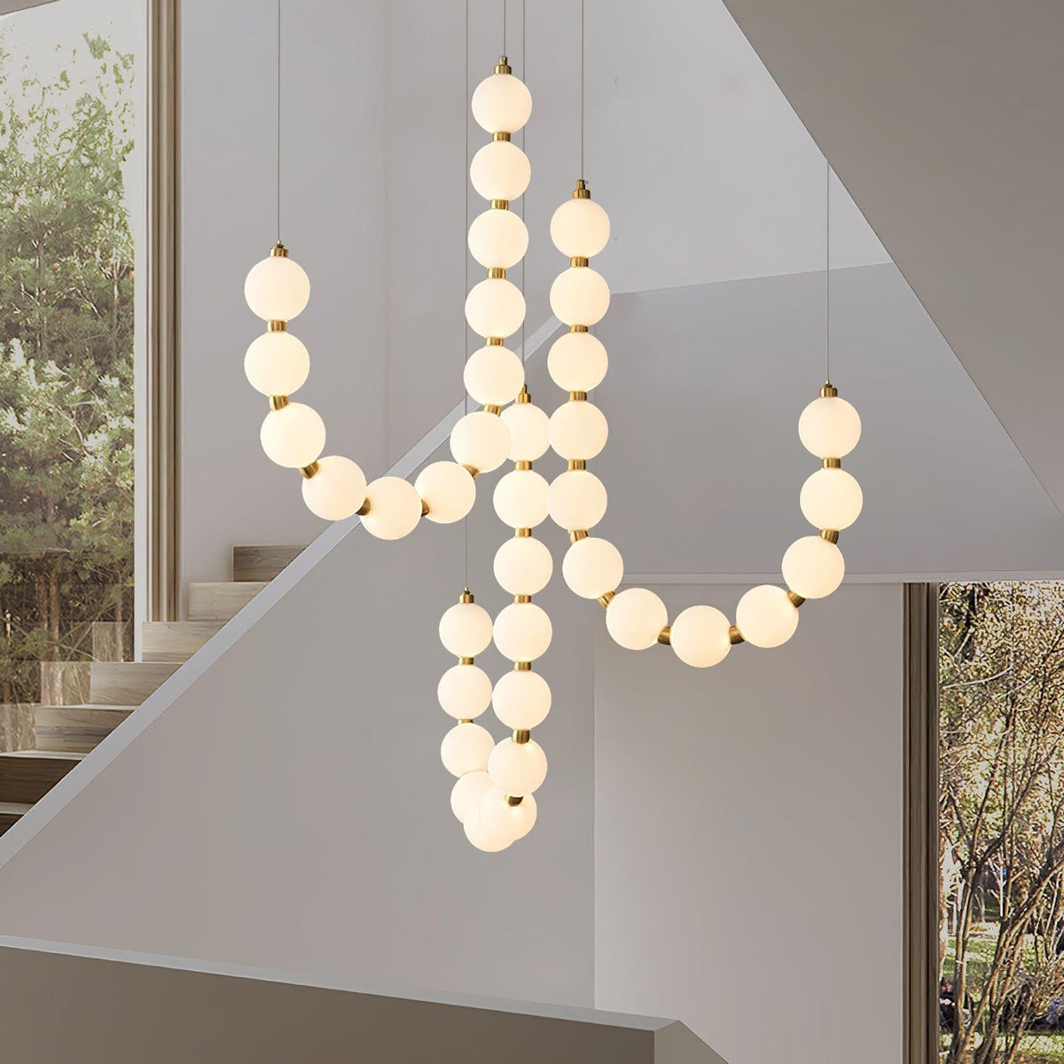 Perloria Chandelier, looping strands of lit opal globes in a bright stairwell