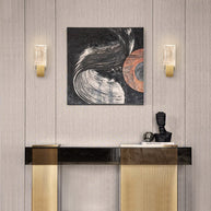 Two of the wall lights lit either side of a framed picture above a console table.