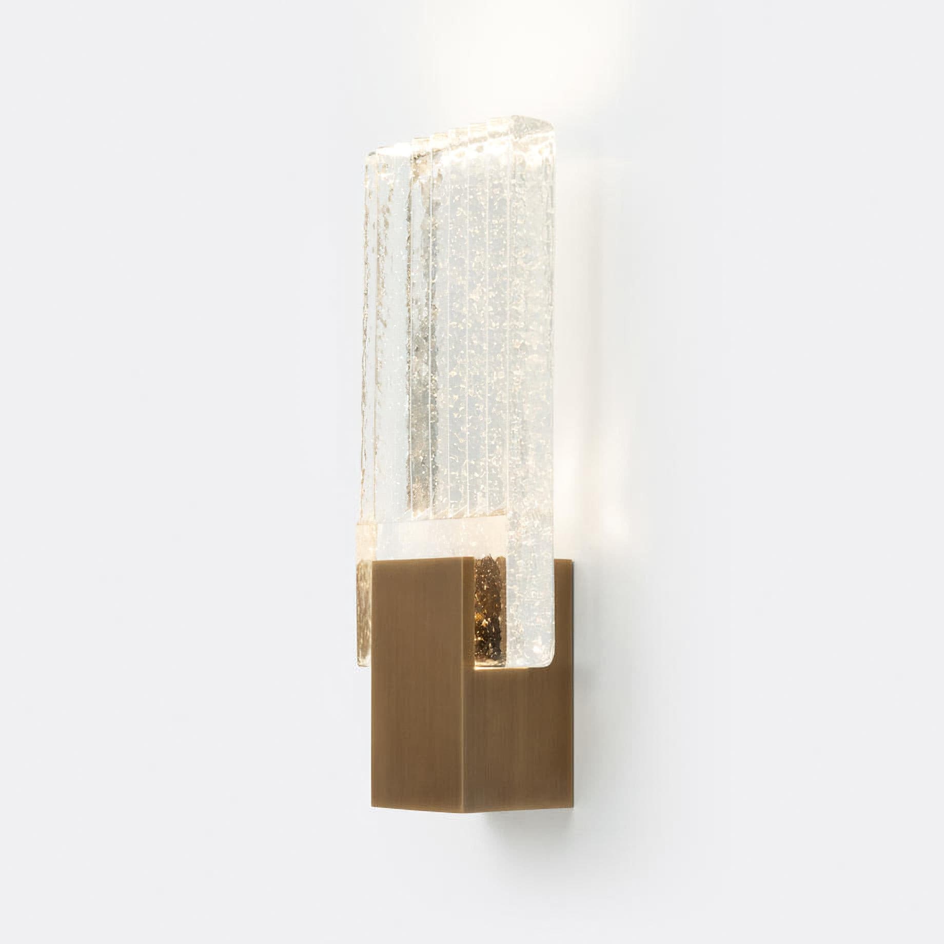 Wall light with a ribbed clear glass panel and a gold-toned metal mount, lit, on a white background, with light spilling above and below the glass.
