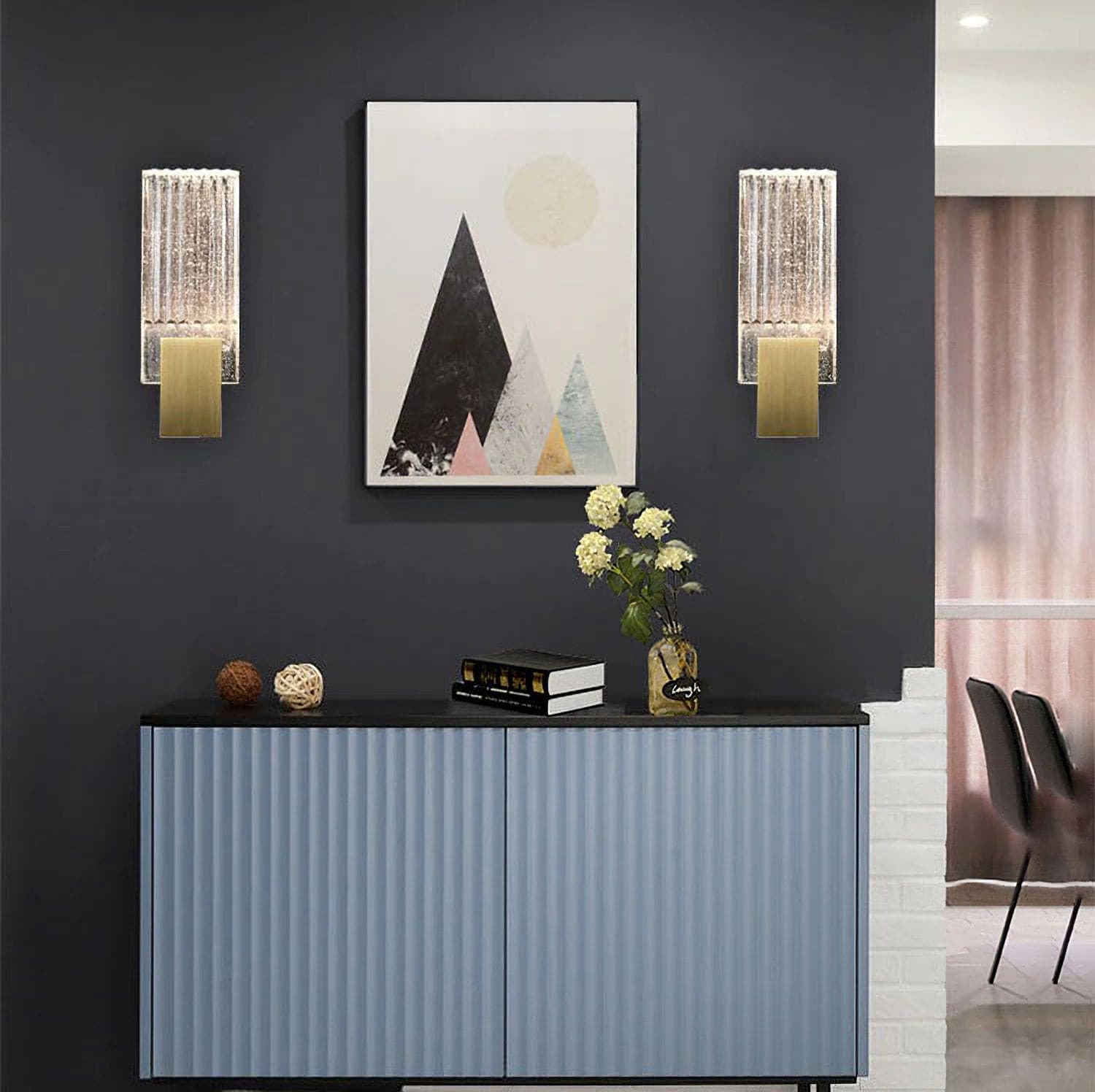 Two of the wall lights lit either side of a framed print above a sideboard.
