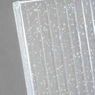 Close view of the glass panel edge showing the ribs and trapped bubbles.