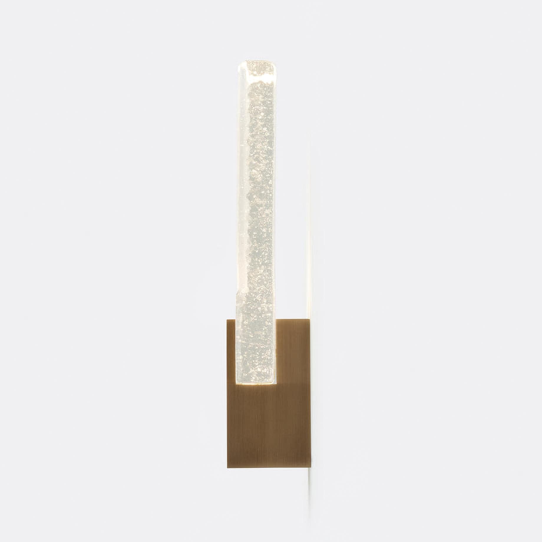 Wall light with a ribbed clear glass panel and a brushed brass mount lit, shown tall on a plain background.