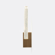 Wall light with a ribbed clear glass panel and a brushed brass mount lit, shown tall on a plain background.