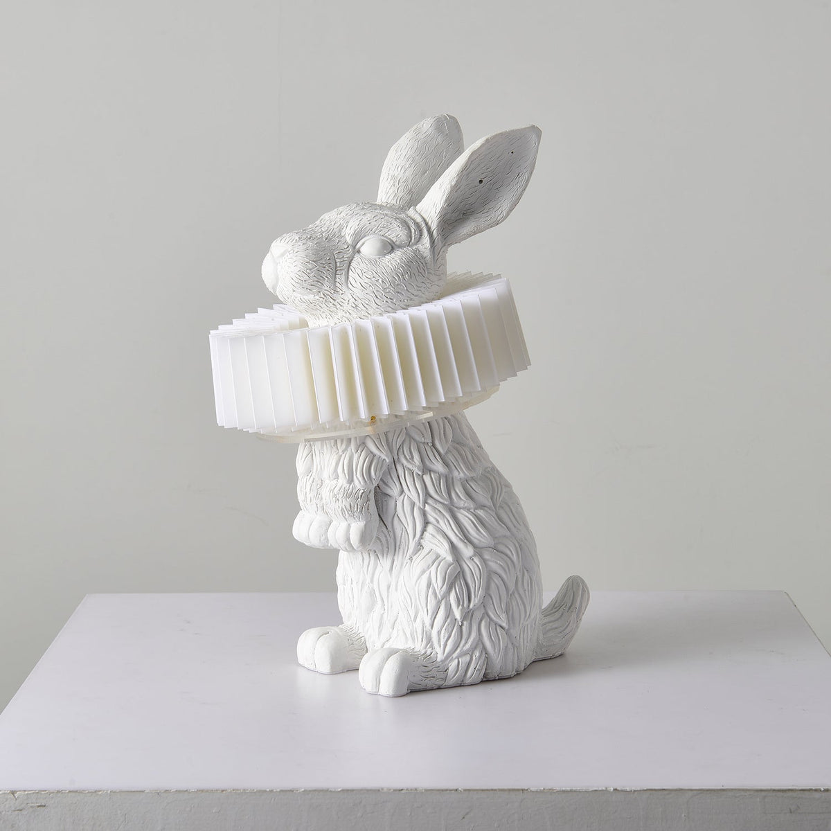 Rabellin Table Lamp - seated white leaf-textured rabbit with pleated ruff shade, unlit on a white plinth
