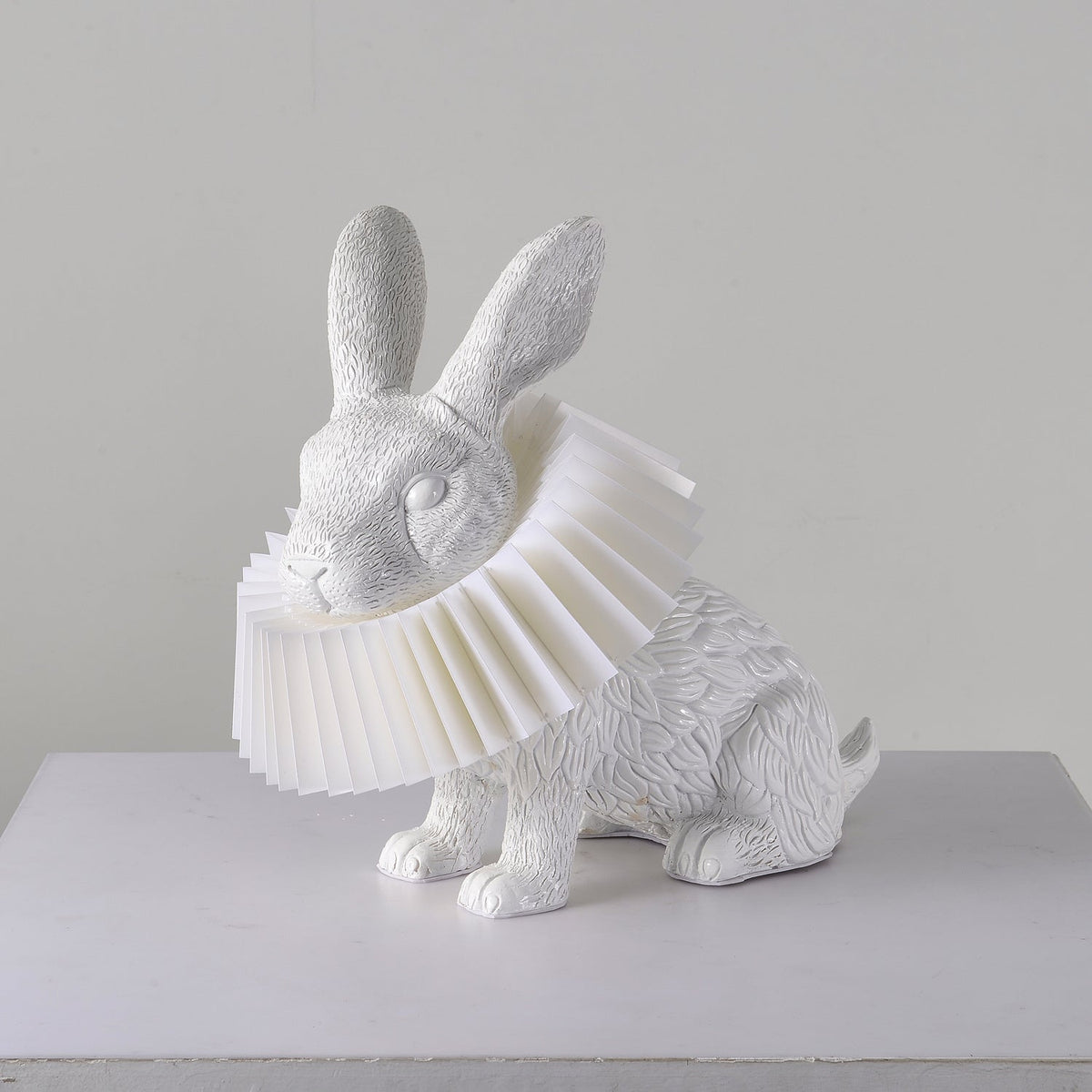 Rabellin Table Lamp - seated white leaf-textured rabbit with pleated ruff shade, unlit on a white plinth