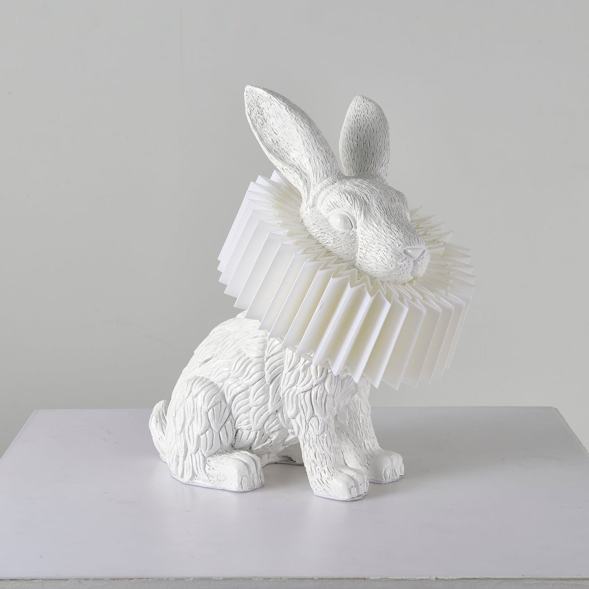 Rabellin Table Lamp - seated white leaf-textured rabbit with pleated ruff shade, unlit on a white plinth