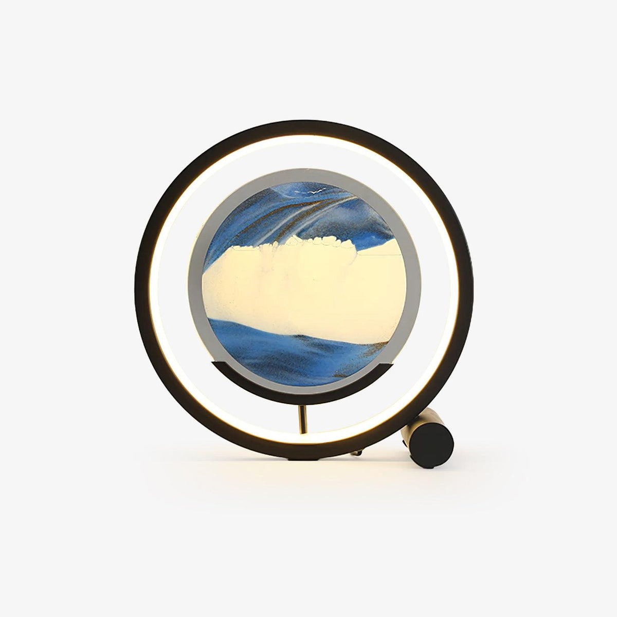 Sandrelle Table Lamp in black with lit LED ring and round blue sand art panel on a plain light background
