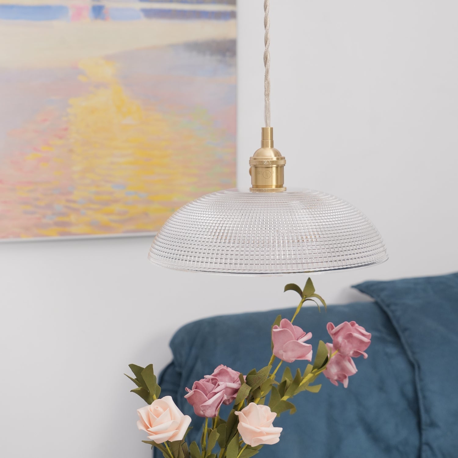 Pendant light with a ribbed glass dome shade and a gold-toned lamp holder hanging above roses, seen from a little further back.