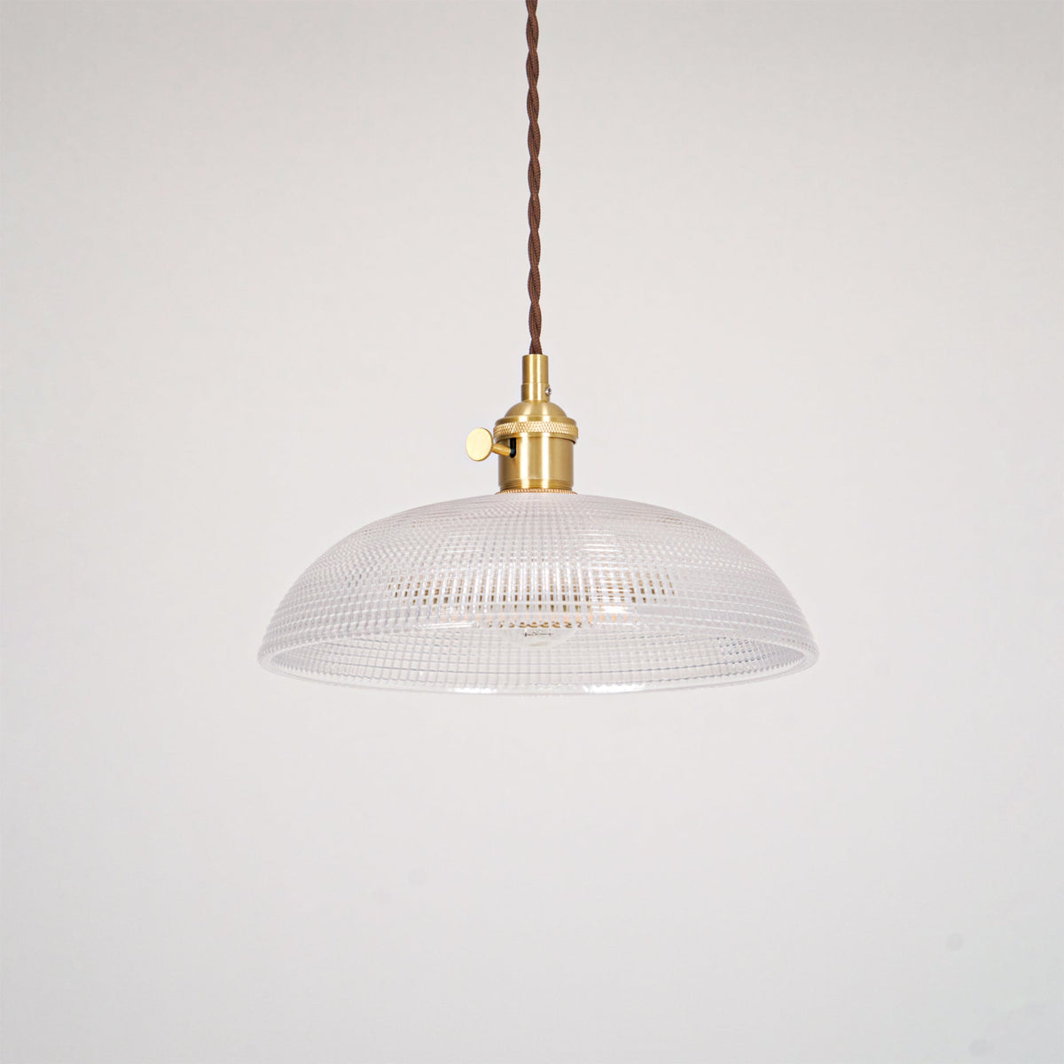 Pendant light with a ribbed glass dome shade and a gold-toned lamp holder, unlit, shown on a plain grey background.