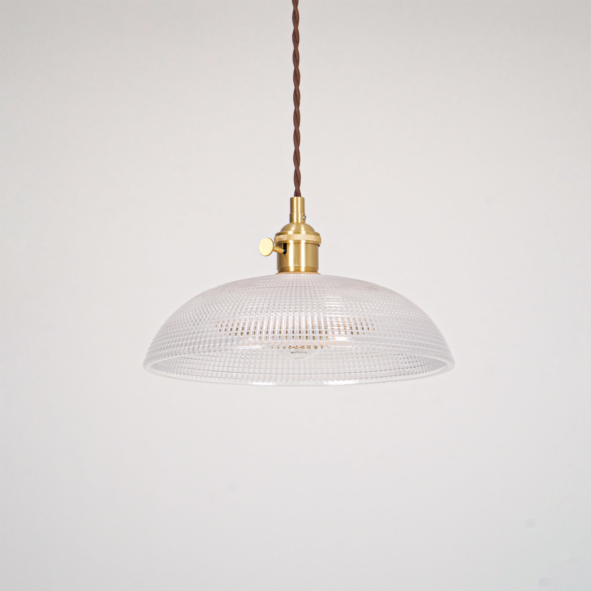 Pendant light with a ribbed glass dome shade and a gold-toned lamp holder, unlit, shown on a plain grey background.