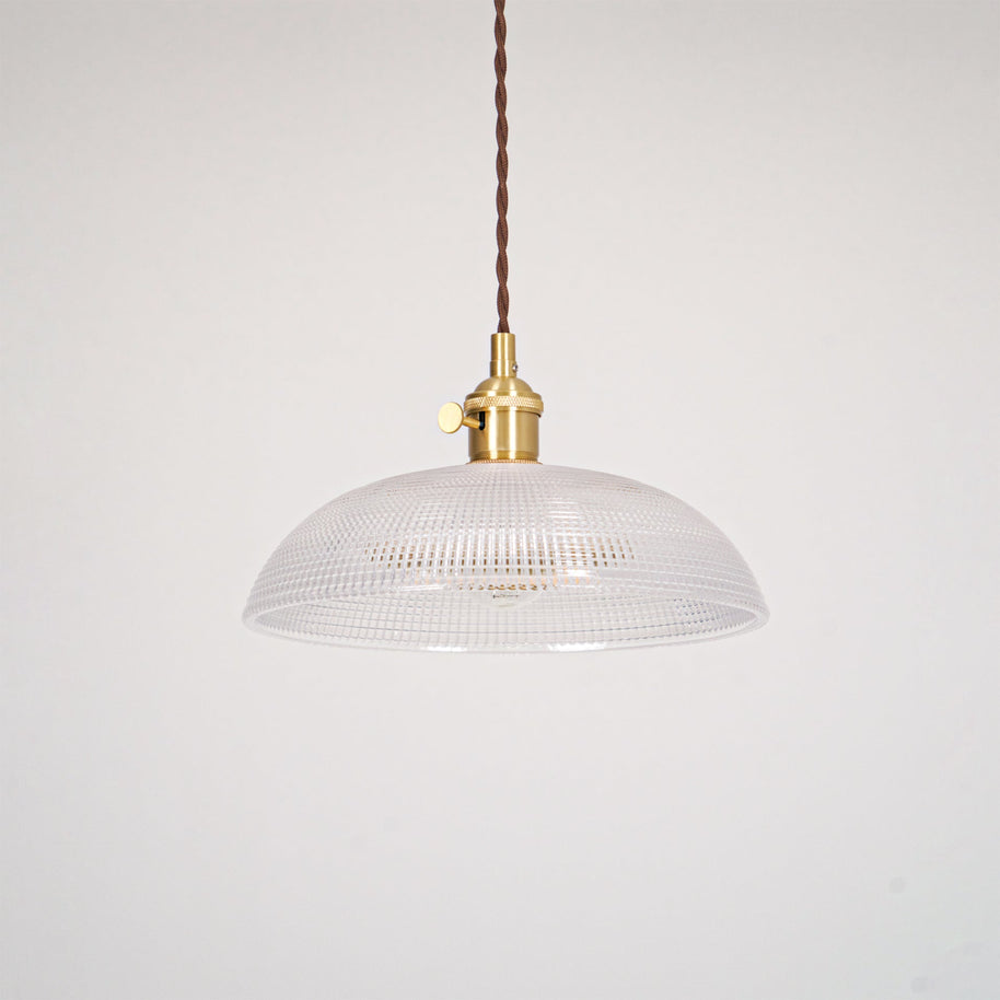 Pendant light with a ribbed glass dome shade and a gold-toned lamp holder, unlit, shown on a plain grey background.
