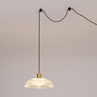 Pendant light with a ribbed glass dome shade and a gold-toned lamp holder hung on a looped cable from hooks in the ceiling.