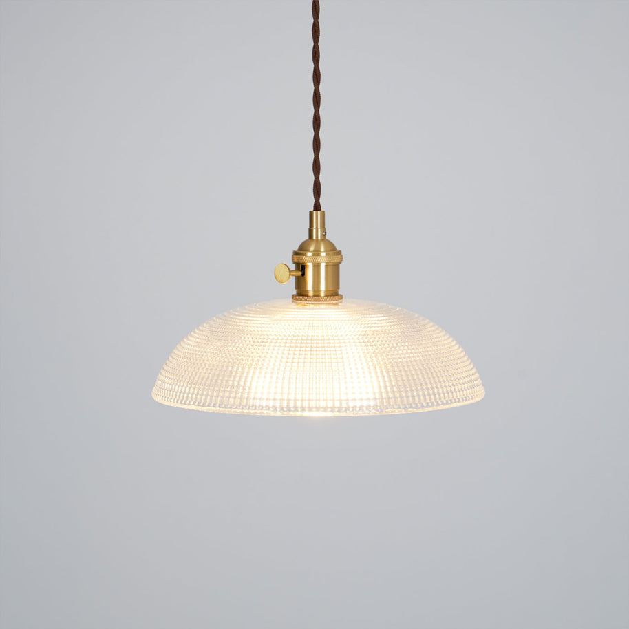 Pendant light with a ribbed glass dome shade and a gold-toned lamp holder, lit, shown on a plain grey background.