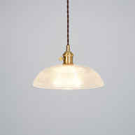 Pendant light with a ribbed glass dome shade and a gold-toned lamp holder, lit, shown on a plain grey background.