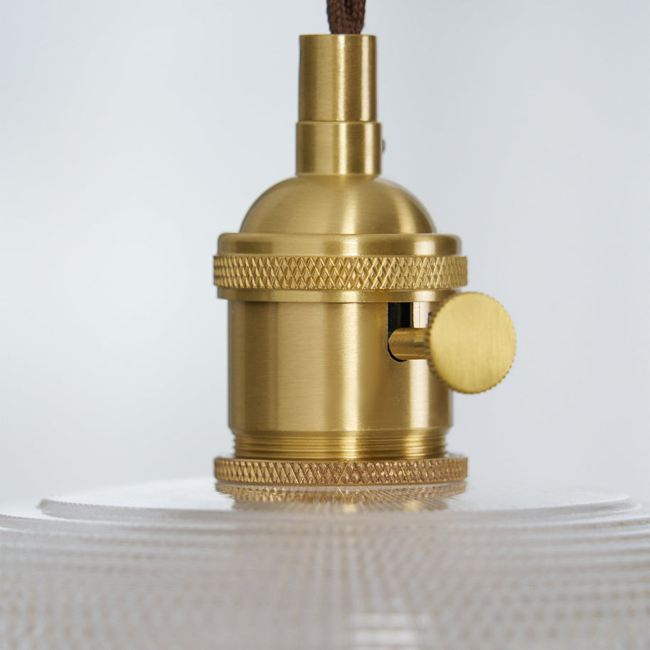 Close view of the gold-toned lamp holder and knurled collar above the glass shade.