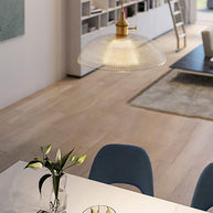 Pendant light with a ribbed glass dome shade and a gold-toned lamp holder, lit, hanging over a counter with books and a vase.