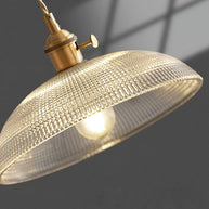 Close view of the ribbed glass dome shade and the gold-toned lamp holder, lit, against a dark background.