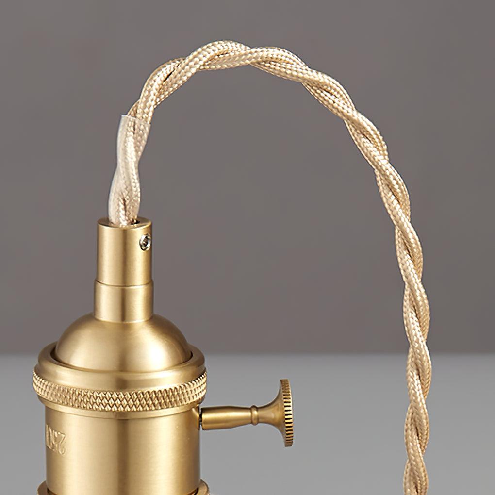 Close view of the twisted fabric cable curving into the gold-toned lamp holder.