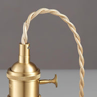 Close view of the twisted fabric cable curving into the gold-toned lamp holder.