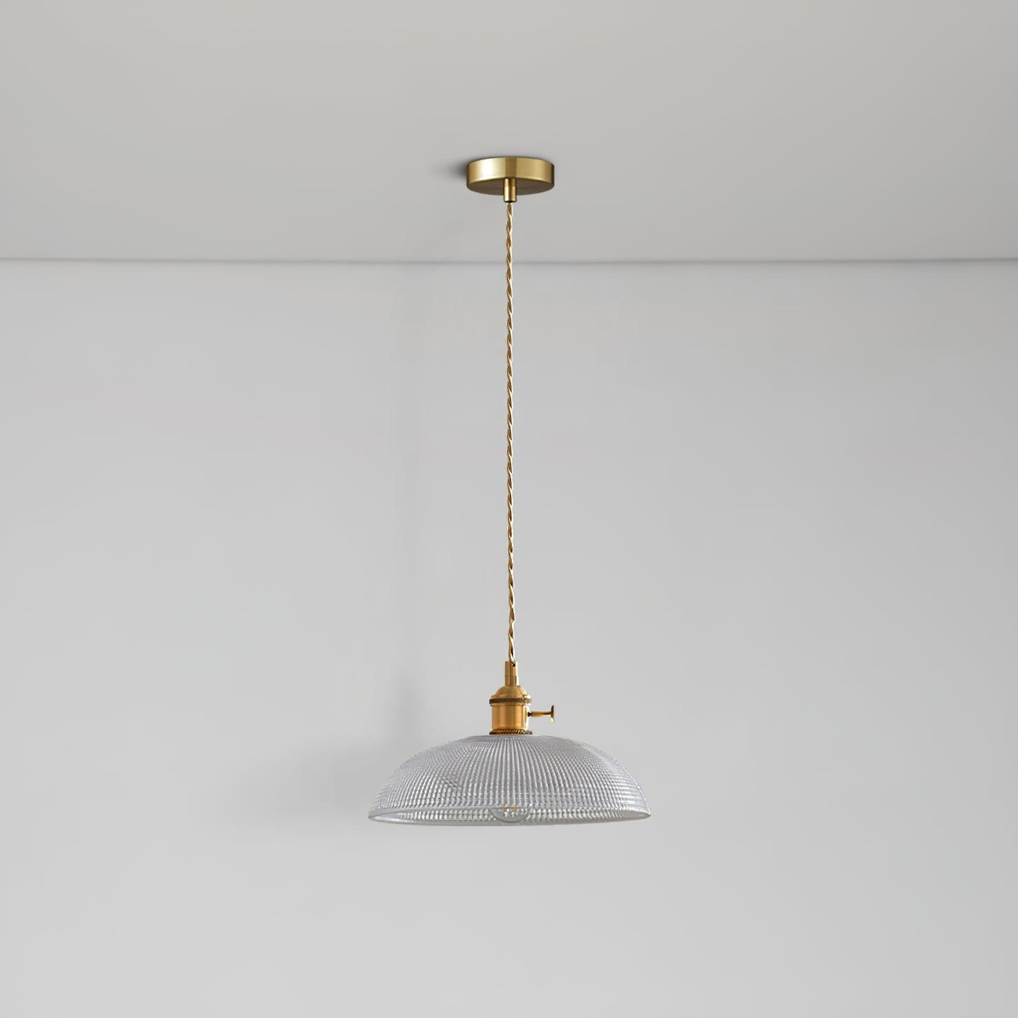 Pendant light with a ribbed glass dome shade and a gold-toned lamp holder hanging from a ceiling rose on a twisted fabric cable, unlit.