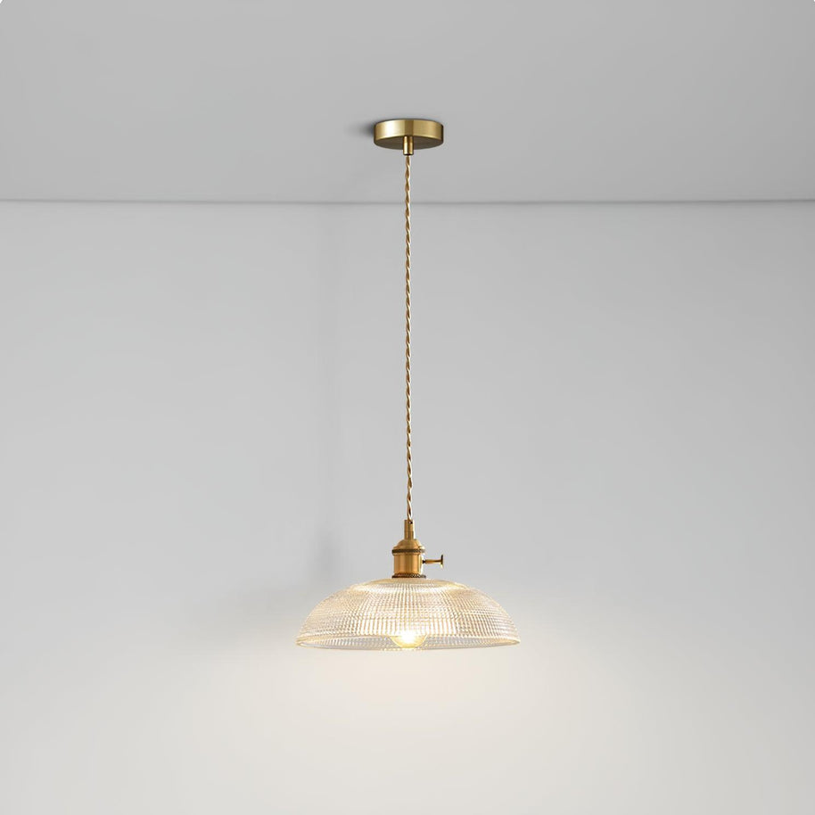 Pendant light with a ribbed glass dome shade and a gold-toned lamp holder hanging from a ceiling rose on a twisted fabric cable, lit softly.